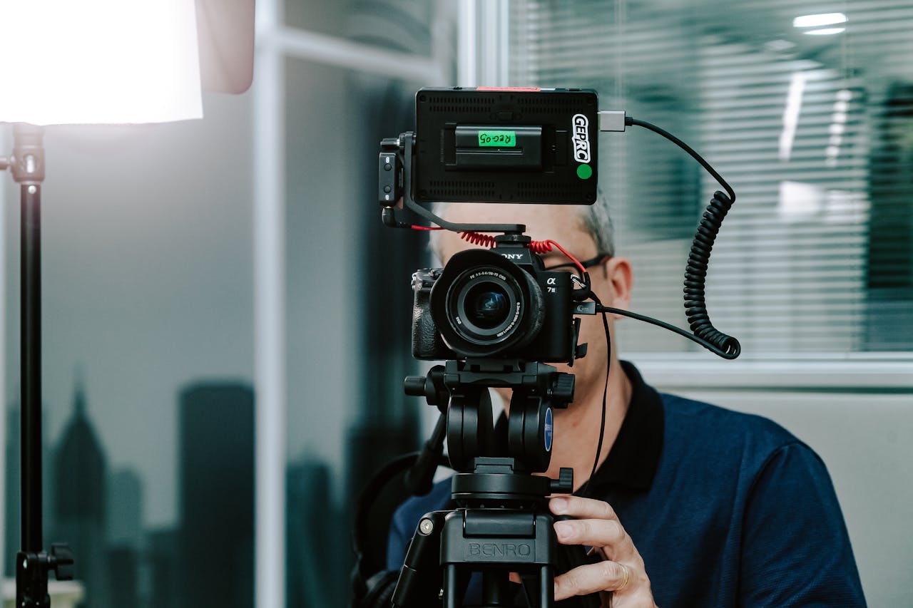 A videographer setting up a camera with additional gear in a modern studio environment.